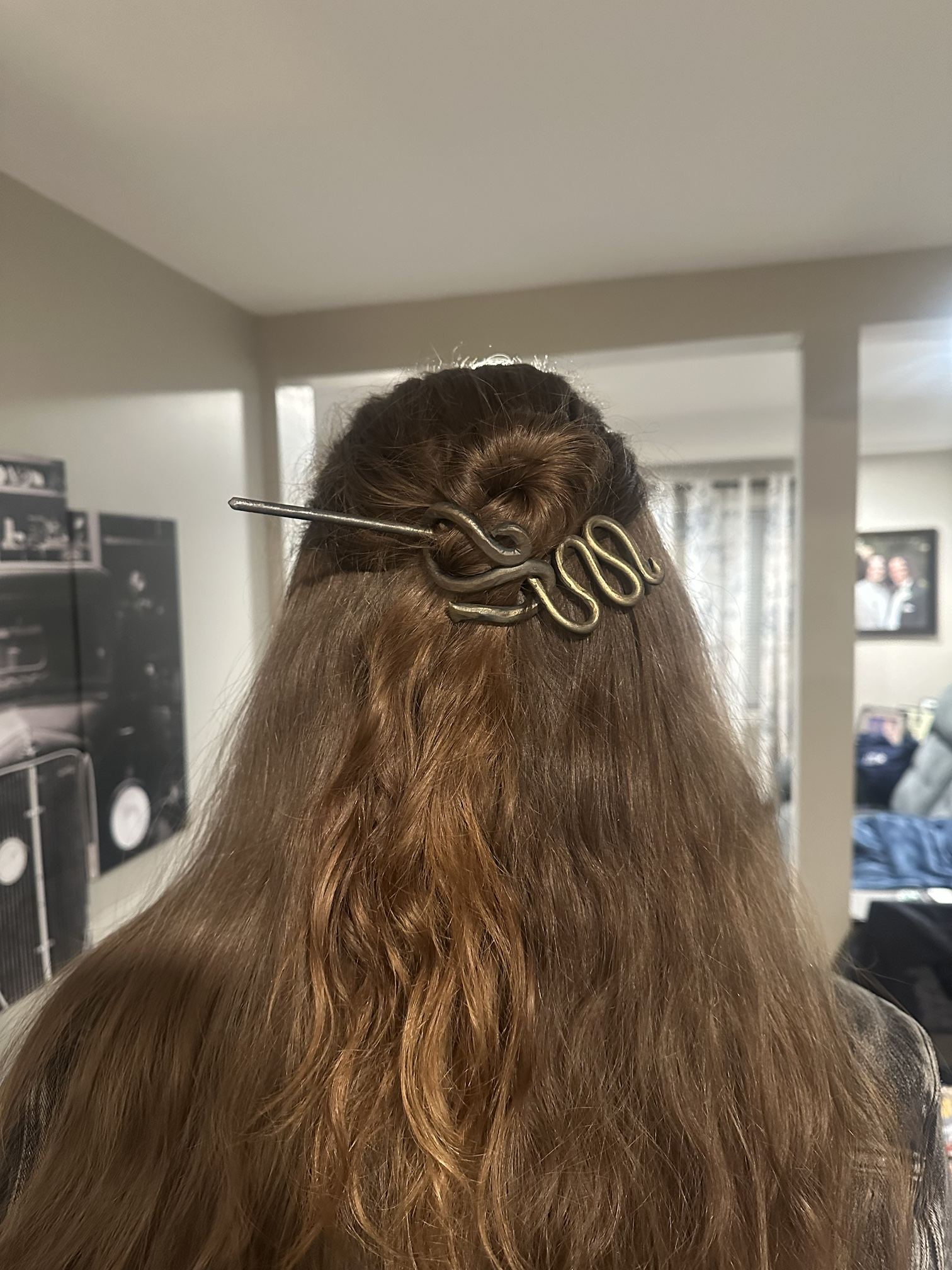 A wavy forged hair slide with a straight pin, worn in long hair.