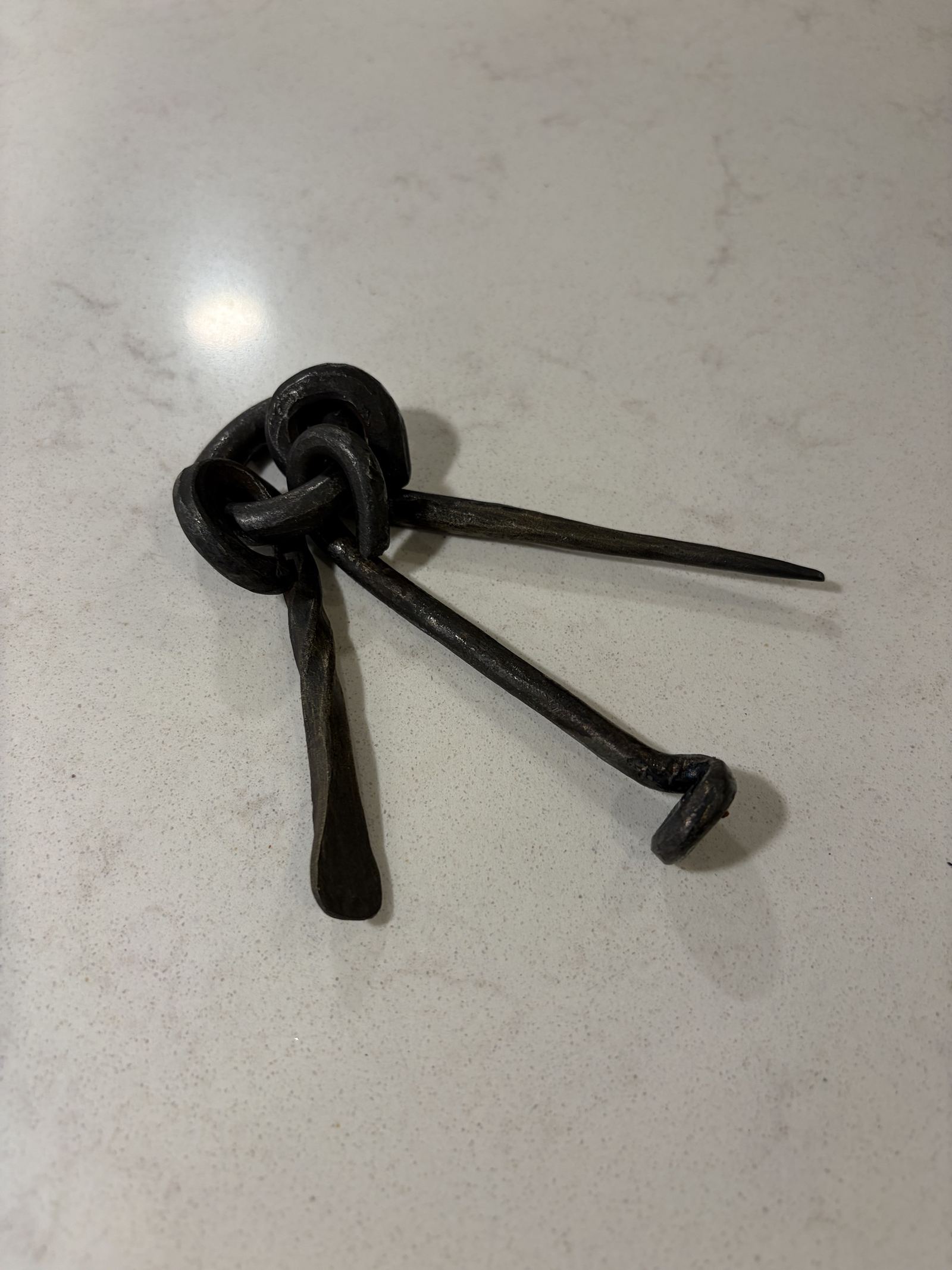 Three hand-forged pipe tools, a pointed pick, a twisted scoop and a tamper, linked on a forged ring.