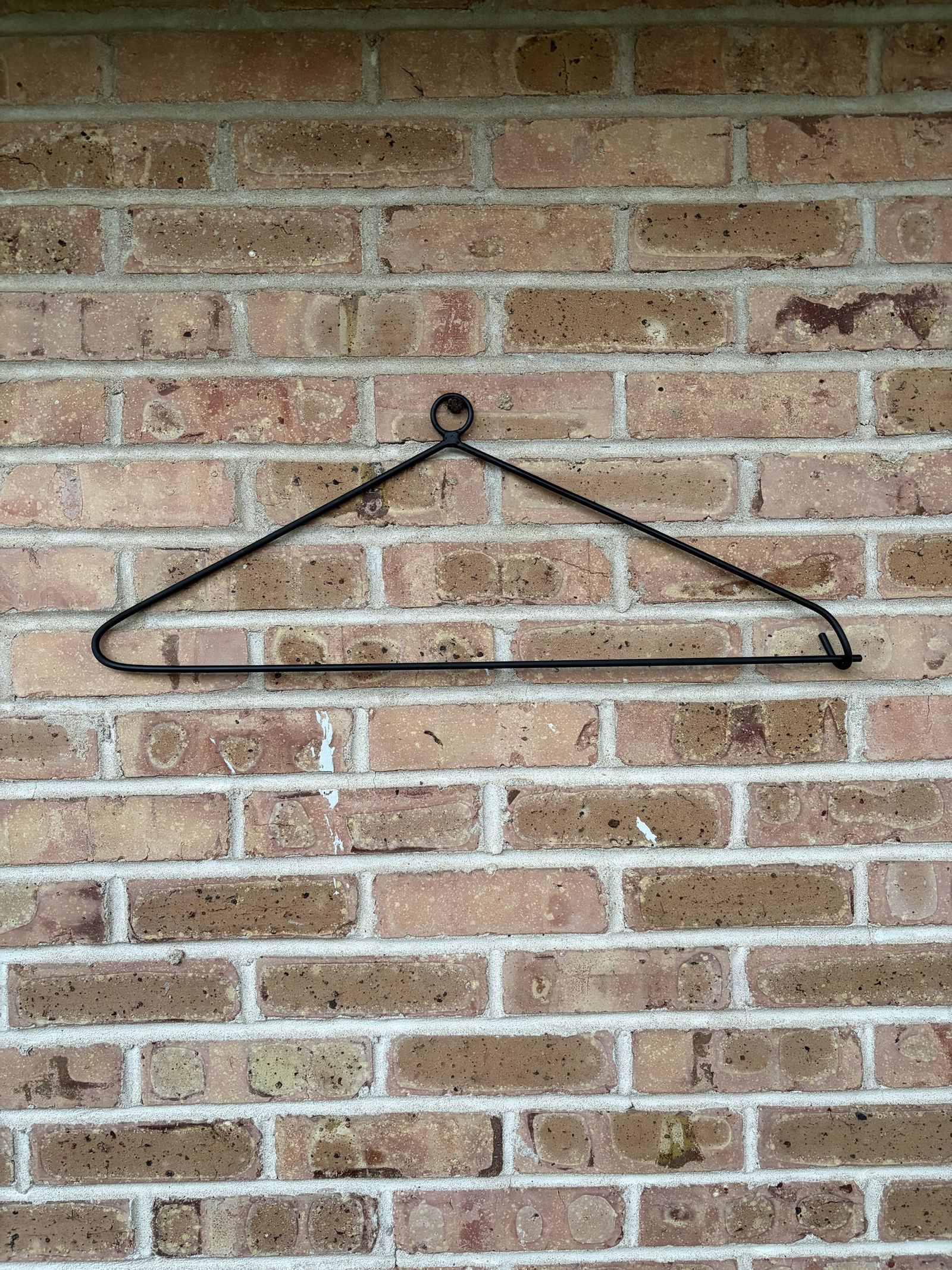The quilt hanger on brick with the bottom bar closed into the hook.